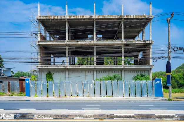 Asia Edificio comercial en proceso de construcción junto a la carretera con fachada de chapa galvanizada y valla alrededor Tailandia