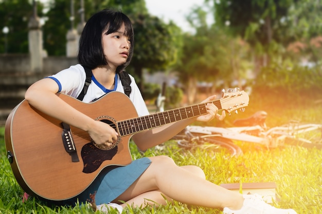 Asia encantadora, adolescente, niña tocando la guitarra sola con soledad y tristeza