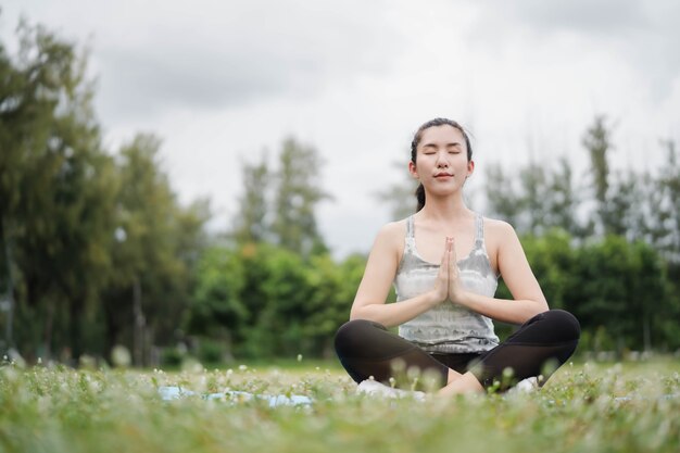 Asia-Frau praktiziert Yoga und meditiert im Park. Gesunder Lebensstil und Yoga-Konzept.