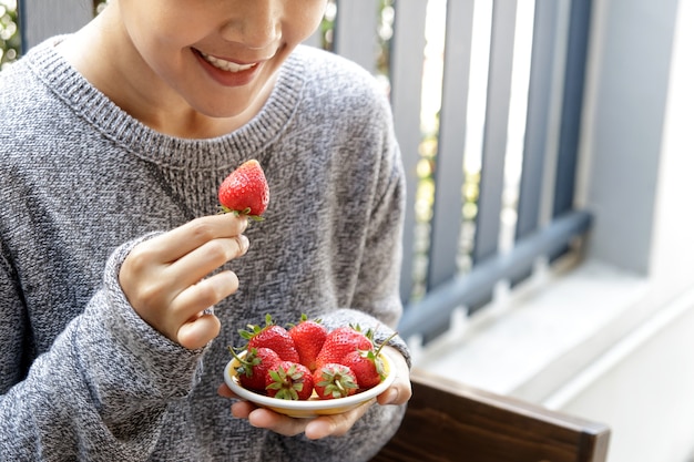 Foto asia hermosa joven mujer comiendo fresas frescas.
