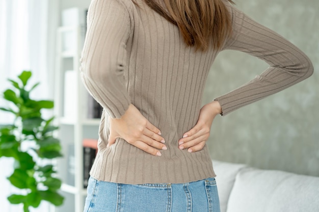Asia hermosa mujer sosteniendo su espalda baja mientras sufre de dolor insoportable salud y problemas dolor de espalda crónico dolor de espalda en el síndrome de oficina escoliosis hernia discal inflamación muscular