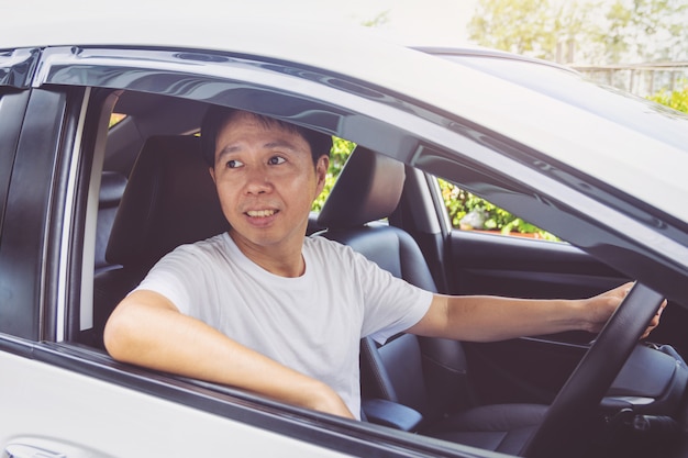 Asia hombre sonrie feliz y maneja coche