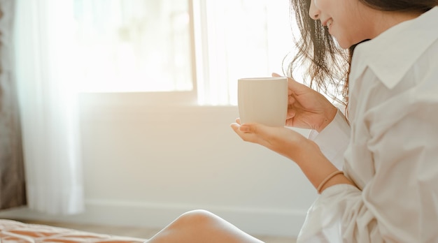 Ásia jovem vivendo em casa, relaxando e bebendo café quente no quarto de férias. asiático, ásia, relaxe, sozinho, tecnologia, conceito de estilo de vida.