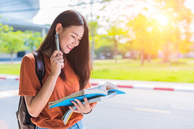 Asia joven mujer universitaria haciendo la tarea y leyendo libros para el examen final en el campus