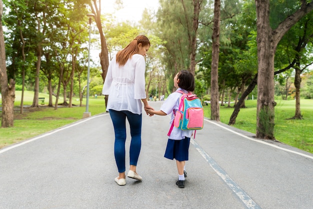 Asia madre e hija estudiante caminando a la escuela.