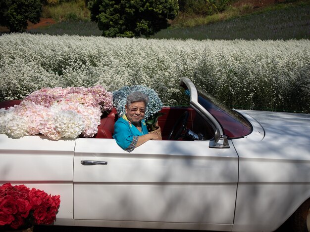 Asia mujer anciana anciana senior montando coche clásico retro con flor de hortensia en cortador de jardín aster