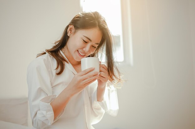 Asia mujer joven despierta refrescado por la mañana y relajarse comer café, copos de maíz, pan y manzana para el desayuno en casa de vacaciones. Asia, asia, relax, desayuno, refresco, concepto de estilo de vida.