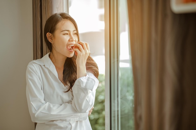 Asia mujer joven despierta refrescado por la mañana y relajarse comer café, copos de maíz, pan y manzana para el desayuno en casa de vacaciones. Asia, asia, relax, desayuno, refresco, concepto de estilo de vida.