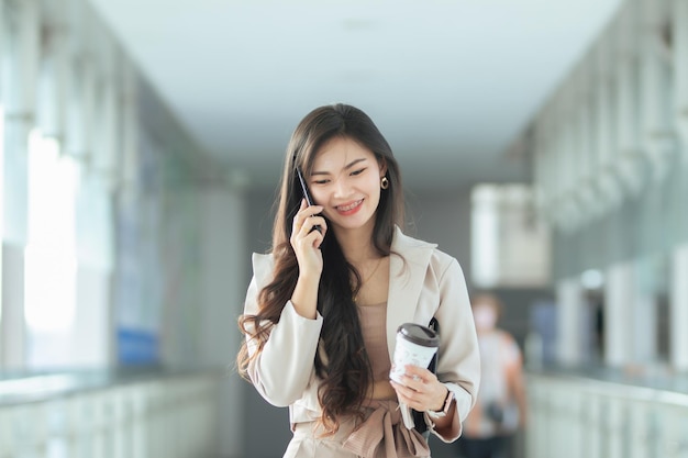 Asia Woman está trabajando en la computadora personal y el teléfono inteligente en el cibercafé