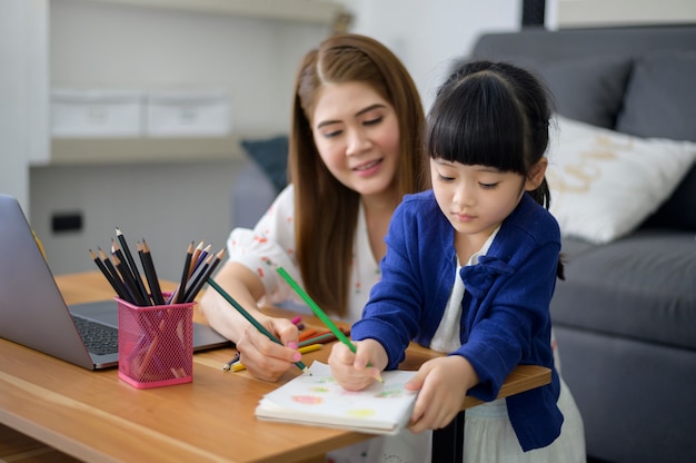 Asian Happy Mutter und Tochter nutzen Laptop, um zu Hause online über das Internet zu lernen. E-Learning-Konzept während der Quarantänezeit.