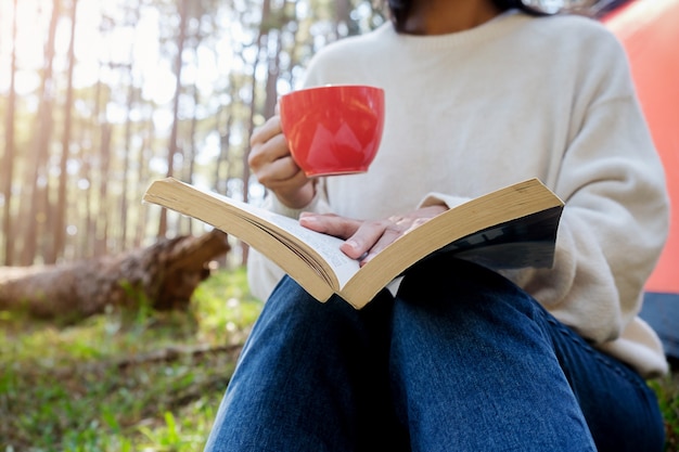 Foto asian hipster menina fofa adolescente curtindo o nascer do sol fora da barraca. acampando na floresta.