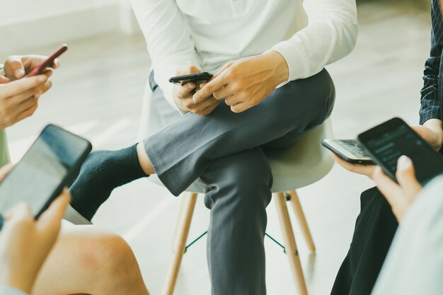 Asiaten sitzen im Kreis zusammen, jeder benutzt ein zentrales Telefon, keiner achtet auf jemanden.