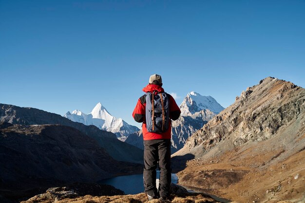 Foto asiater, rucksacker, mann, wanderer, der sich die berge im yading nationalpark in china ansieht