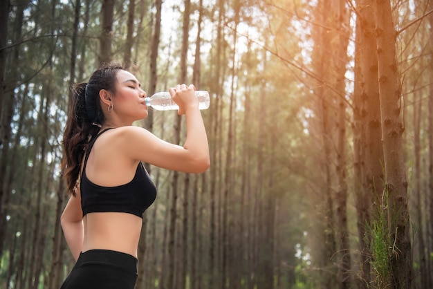 Asiática beleza mulher bebendo água na floresta