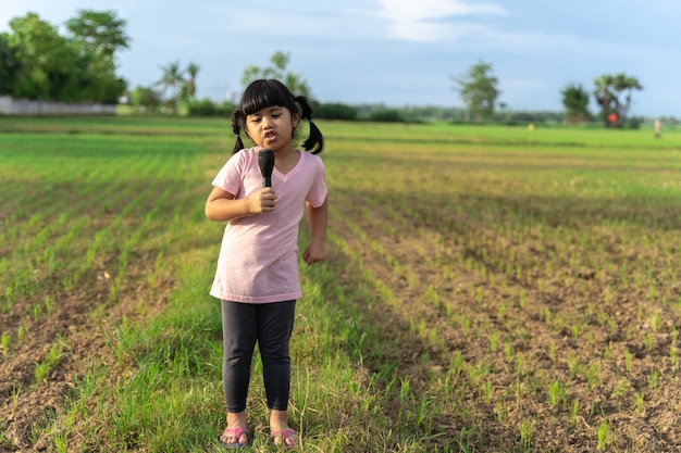 La asiática se para y canta en medio de los campos disfrutando y divirtiéndose.