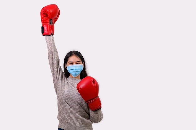 Asiática hermosa joven feliz con máscara de protección y guantes de boxeo que se preparan para la lucha contra el Coronavirus, con espacio de copia