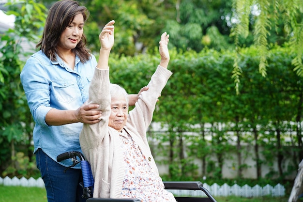 Asiática idosa paciente com deficiência exercício em cadeira de rodas com médico em parque conceito médico