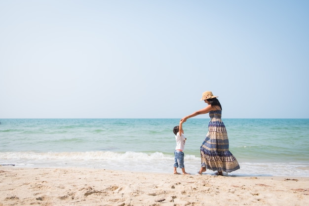 Asiática mãe e filha estão jogando dançando juntos na praia