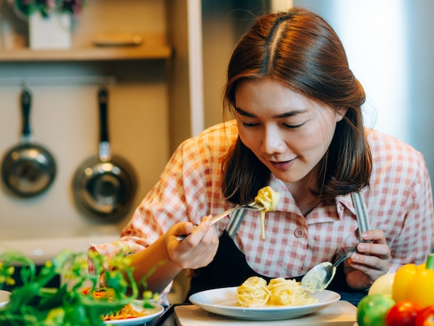 Asiática mulher bonita durante fazer o alimento de espaguete na cozinha