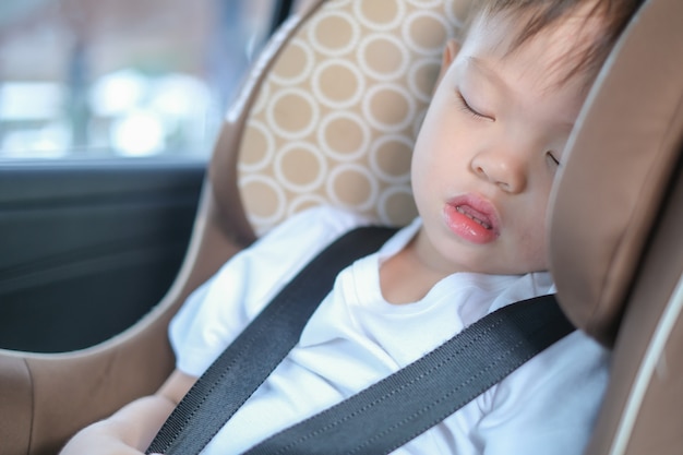 Asiático 2 -3 años niño bebé niño durmiendo en el asiento del automóvil moderno. Niño viajando seguro en la carretera