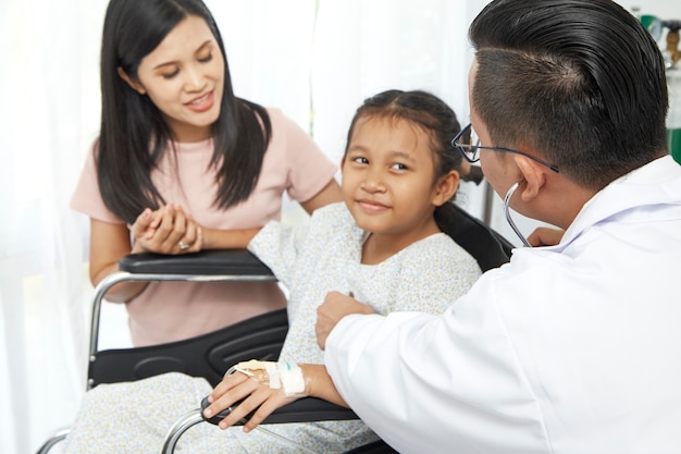 Asiático, doutor masculino, falando, para, criança jovem, cadeira rodas, e, mãe, conceito, cuidado hospital
