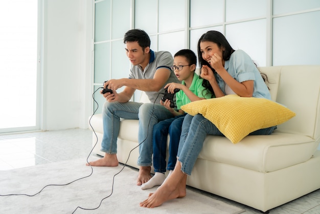 Asiático família pai e filho se divertindo jogando jogos de console do computador