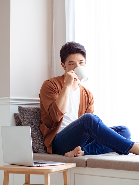 Asiático jovem bonito bebendo em casa