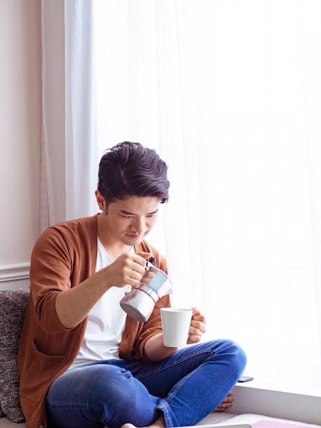 Asiático jovem bonito bebendo em casa