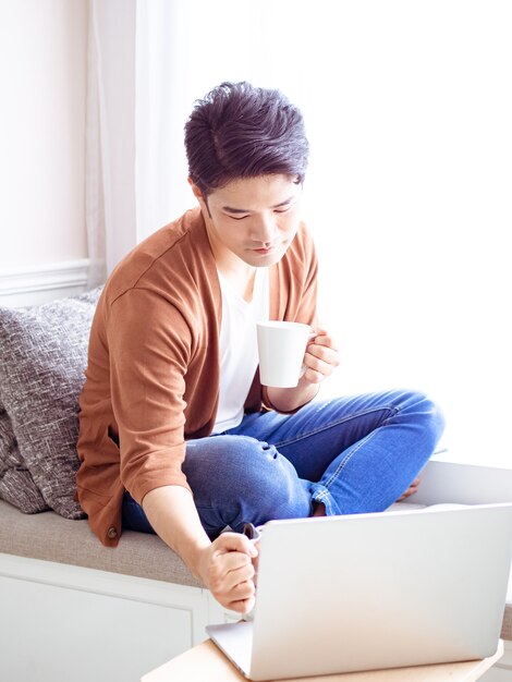 Asiático jovem bonito bebendo em casa