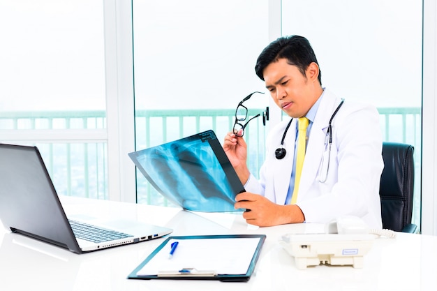 Asiático médico examinando imagens de raio-x na prática