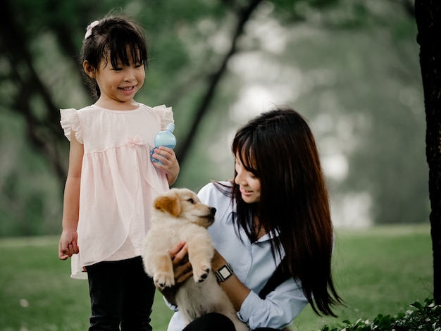 Asiatico y niña jugando wiyh cachorro en el parque