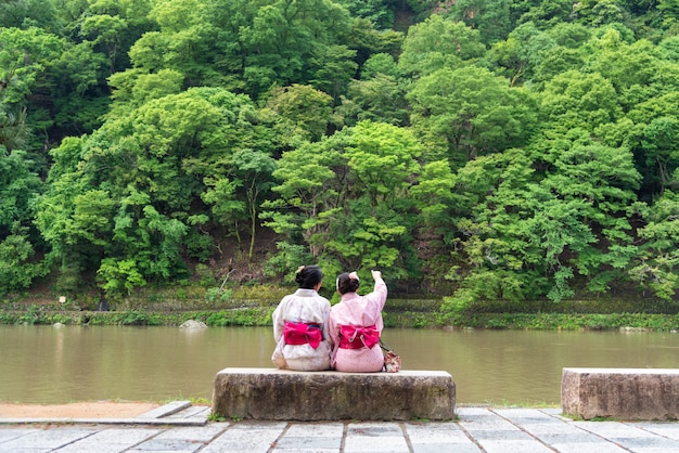 Asiáticos mujer vestida con kimono japonés al lado de un río.