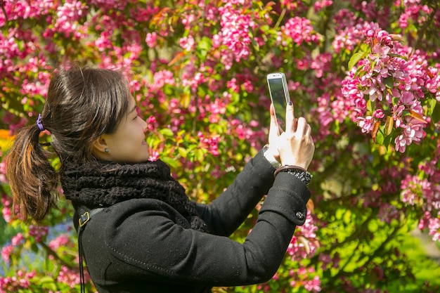 Foto los asiáticos que usan el teléfono inteligente para tomar fotos de los cerezos en flor en tokio, japón.