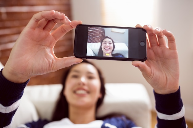 Asiatin auf der Couch, die selfie nimmt