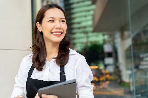 Asiatin barista, das Tablette für die Prüfung der Bestellung vom Kunden hält