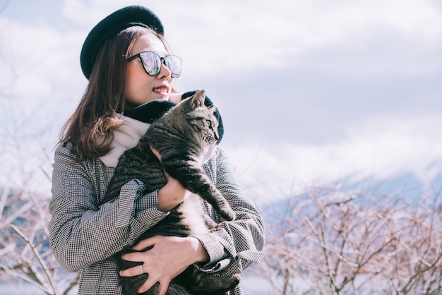 Asiatin, die draußen eine Katze in Japan-Winter hält