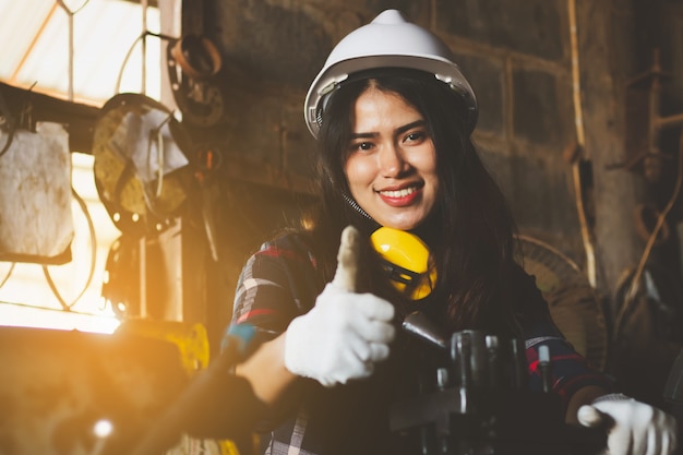 Asiatin, die in der Fabrik, Industrie unter Verwendung der Maschine mit glücklichem arbeitet.