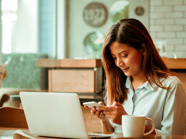 Asiatin, die mit Laptop im Kaffeeshopcafé arbeitet