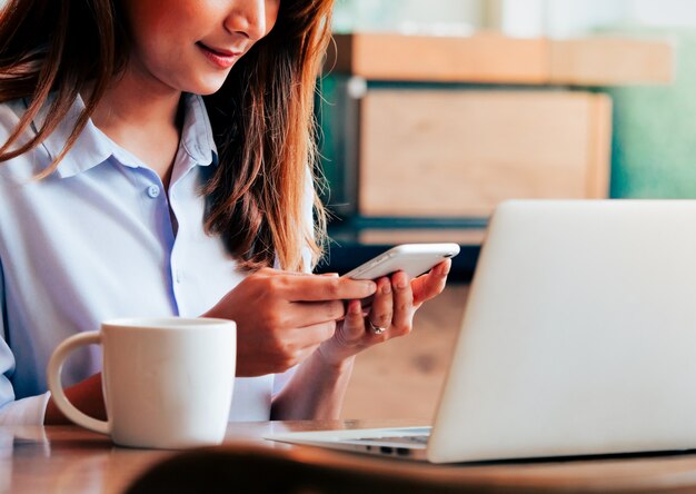 Asiatin, die mit Laptop in der Kaffeestube arbeitet.