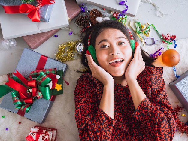 Asiatin, die neues Jahr und Weihnachten auf Boden mit Geschenkbox feiert