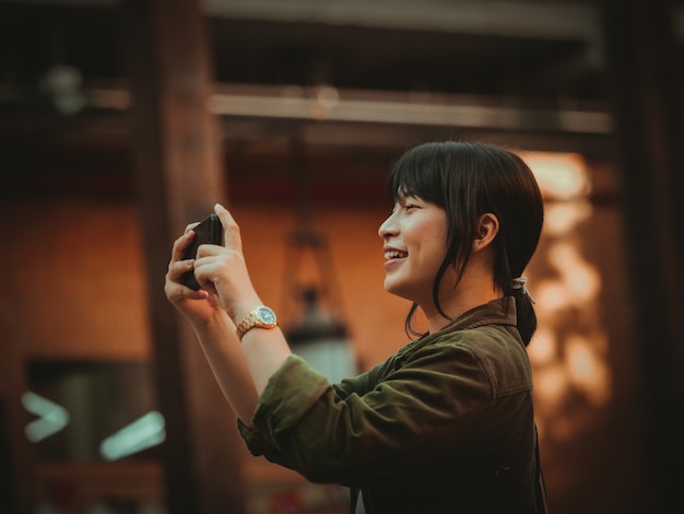 Asiatin, die Smartphone mit glücklicher Stimmung im Einkaufszentrum verwendet