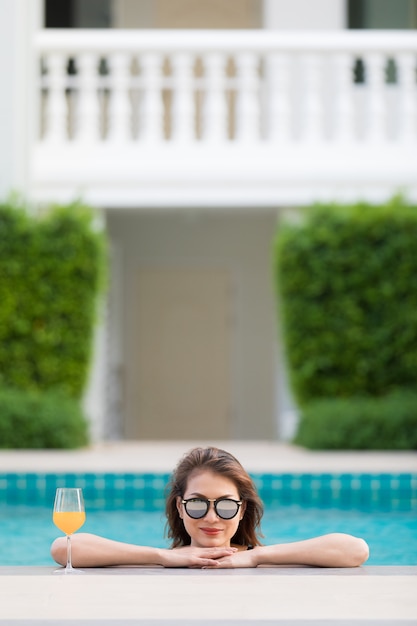 Asiatin im Pool mit Glas Orangensaft