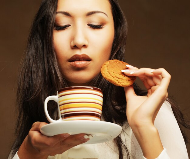 Asiatin mit Kaffee und Plätzchen.