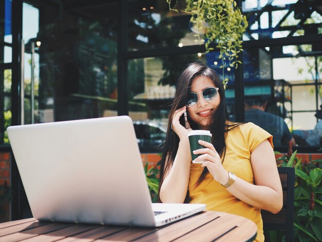 Asiatin mit Laptop in der Kaffeestube