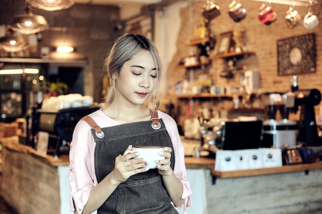 Asiatinnen, die Kaffeetasse am Café halten