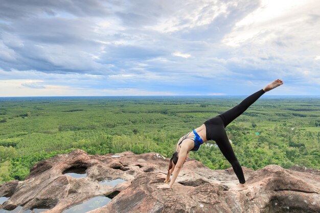 Asiatinnen spielen es Yoga auf der Gebirgsfelsenklippe.