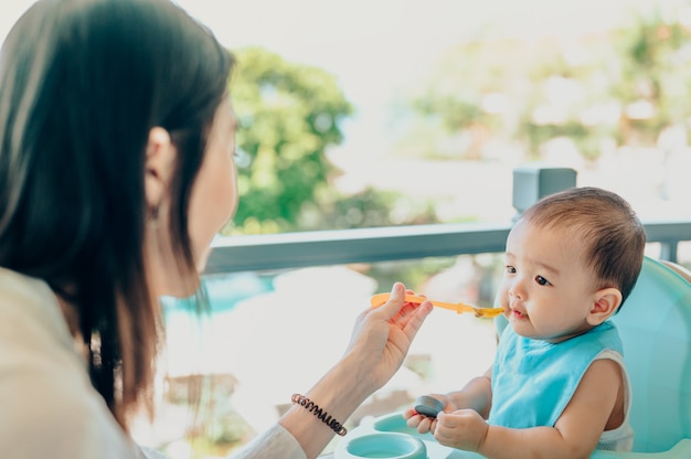 Asiatische 7 Monate Baby essen Mischung Essen auf einem Hochstuhl