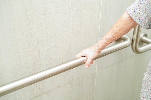 Asiatische ältere alte Patientin benutzt Toilettenstützschiene im Badezimmer Handlauf Sicherheit Haltegriff Sicherheit im Pflegekrankenhaus