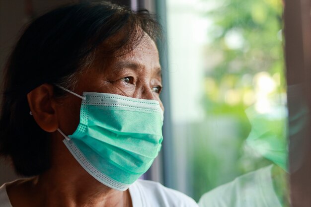 Asiatische ältere Frau, die Masken trägt, die zu Hause leben. Isolation zu Hause, soziale Distanzierung, Coronavirus-Prävention