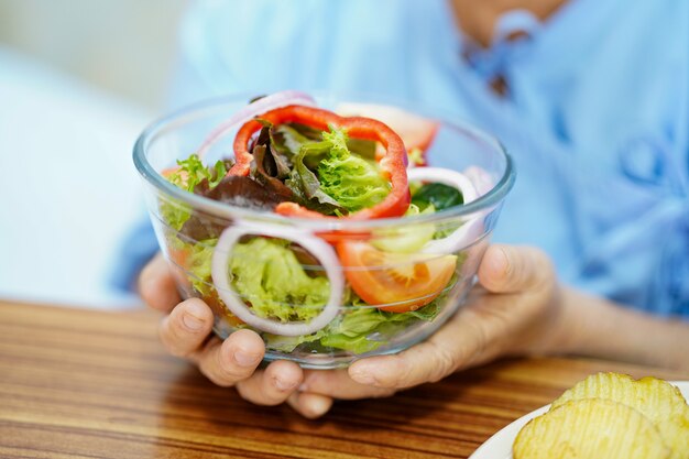 Asiatische ältere Frau, die Salat hält